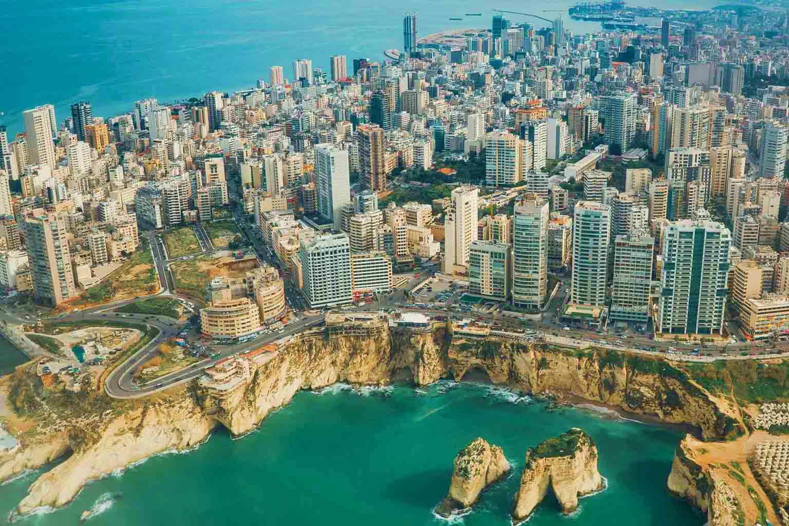 Aerial view of Beirut coastline with dense urban skyline, Mediterranean Sea, and rocky limestone cliffs with Pigeon Rocks
